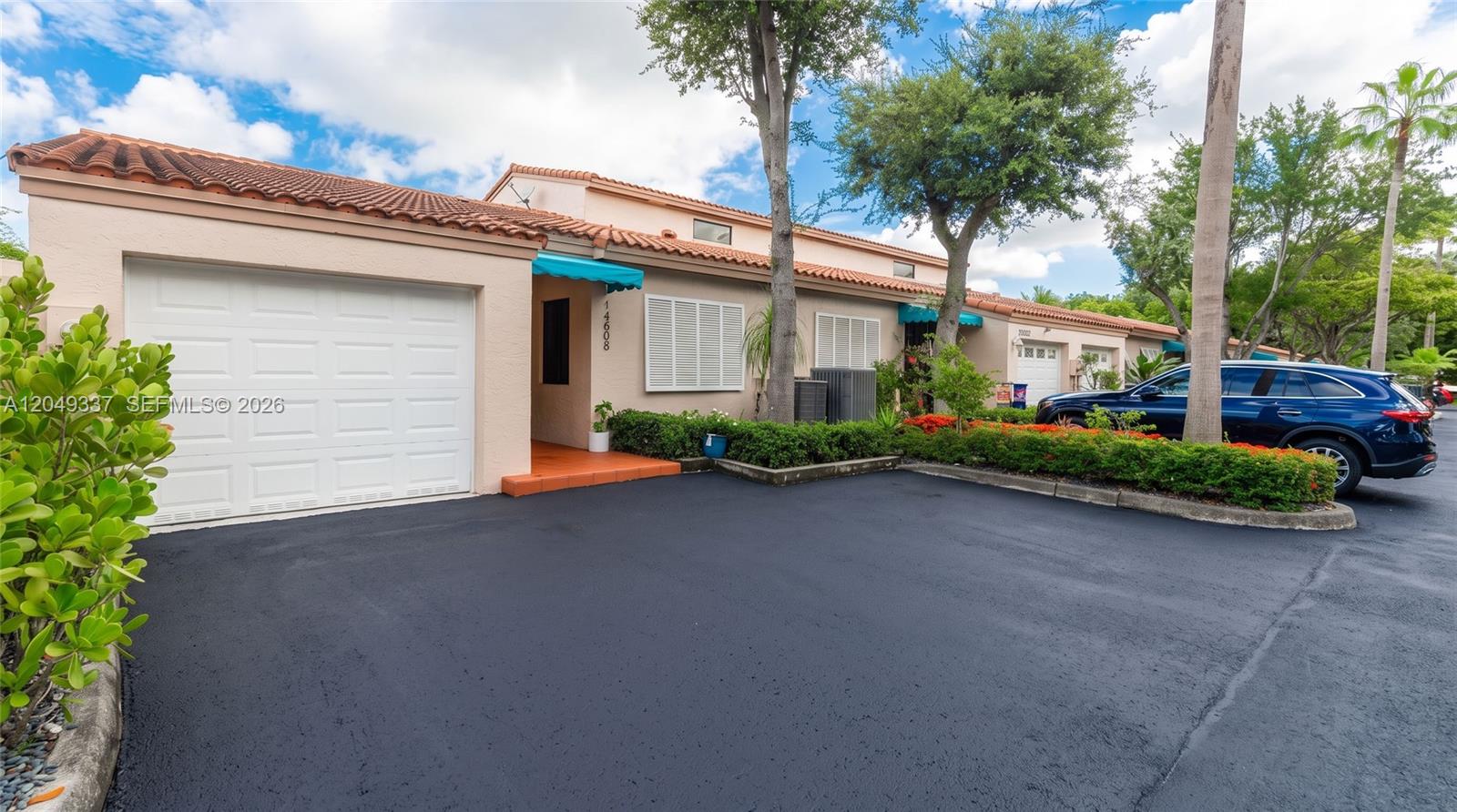 A single-story townhouse with a white garage door, terracotta roof, and a paved driveway — 14808 Balgowan Rd, Miami Lakes FL 33016, MIAMI LAKES, FL