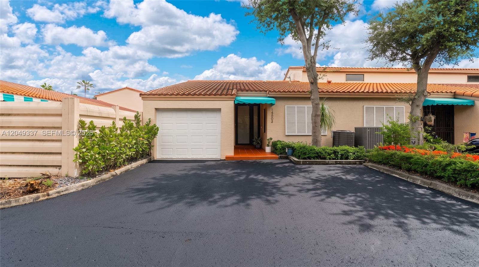 A single-story house features a white garage door, a tiled roof, and a paved driveway — 14808 Balgowan Rd, Miami Lakes FL 33016, MIAMI LAKES, FL
