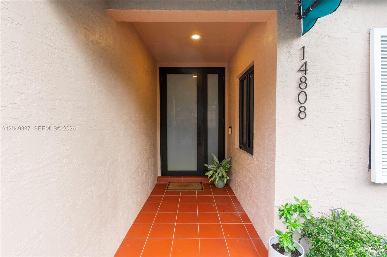 A covered entryway features a frosted glass front door, terracotta tile flooring, and house numbers — 14808 Balgowan Rd, Miami Lakes FL 33016, MIAMI LAKES, FL