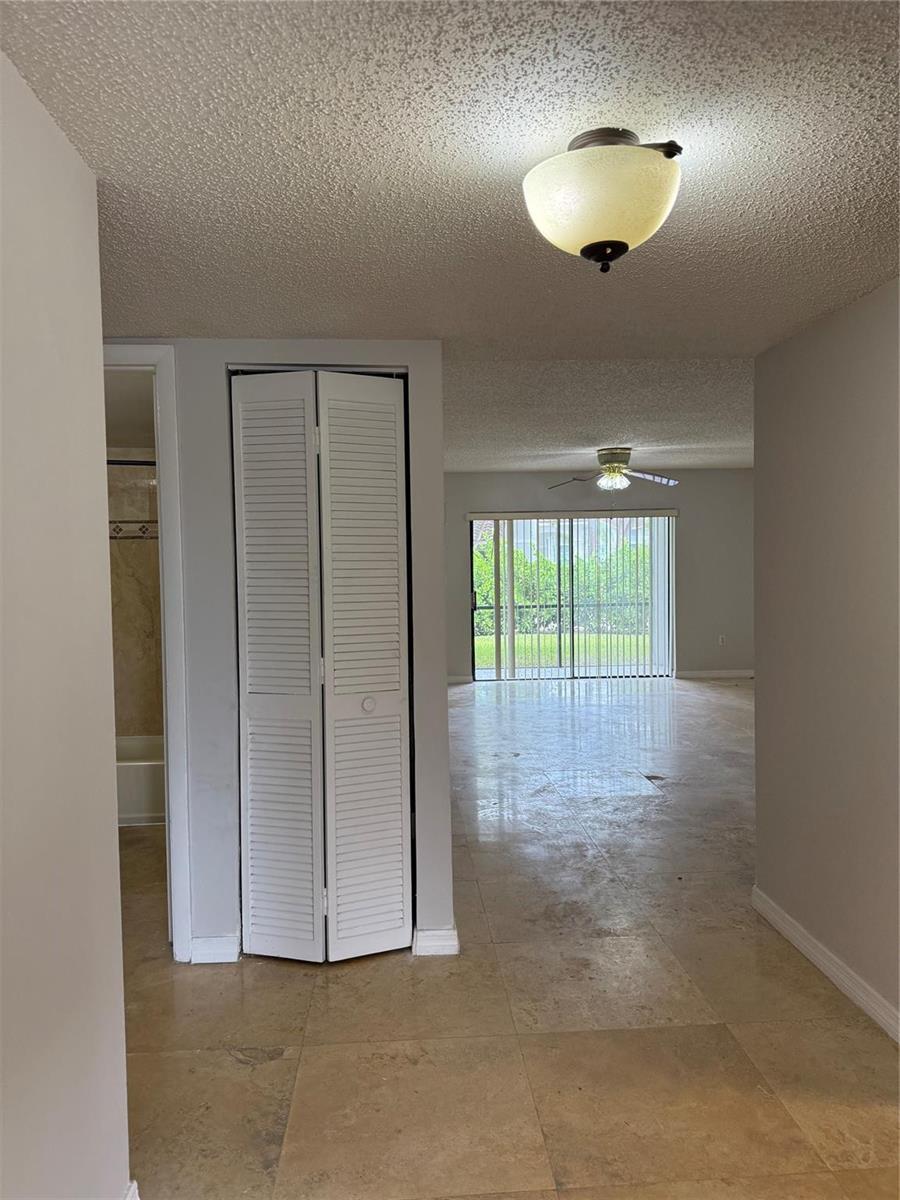 A hallway with tile flooring leads to a living area with a sliding glass door — 8601 NW 34th Place # A102, Sunrise FL 33351, SUNRISE, FL