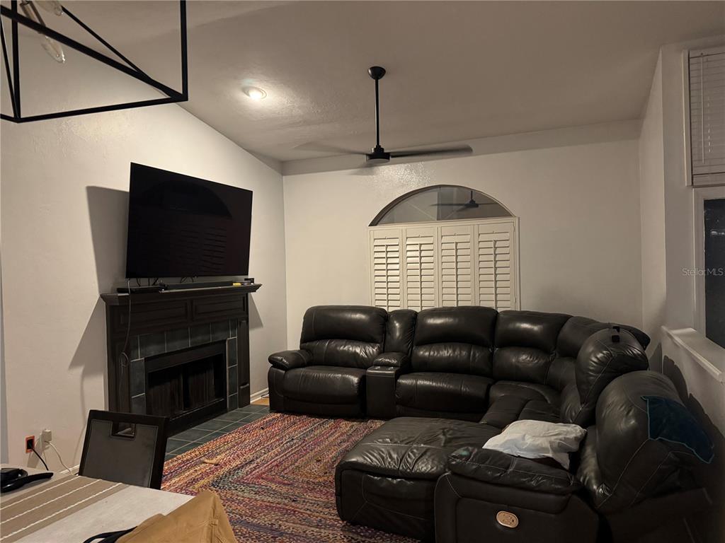 A living room features a dark leather sectional, a fireplace with a television, and shutters — 4924 NW 28TH PLACE, GAINESVILLE, FL