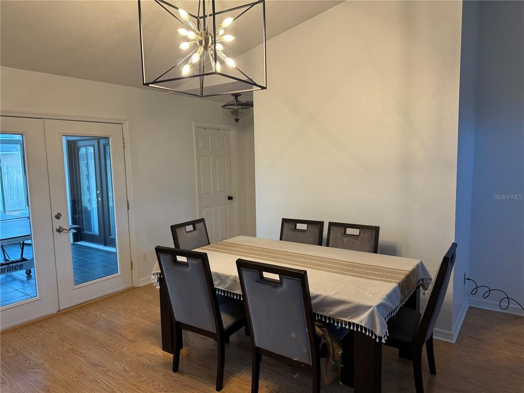 A dining room features a rectangular table with six chairs, a modern chandelier, and glass doors — 4924 NW 28TH PLACE, GAINESVILLE, FL