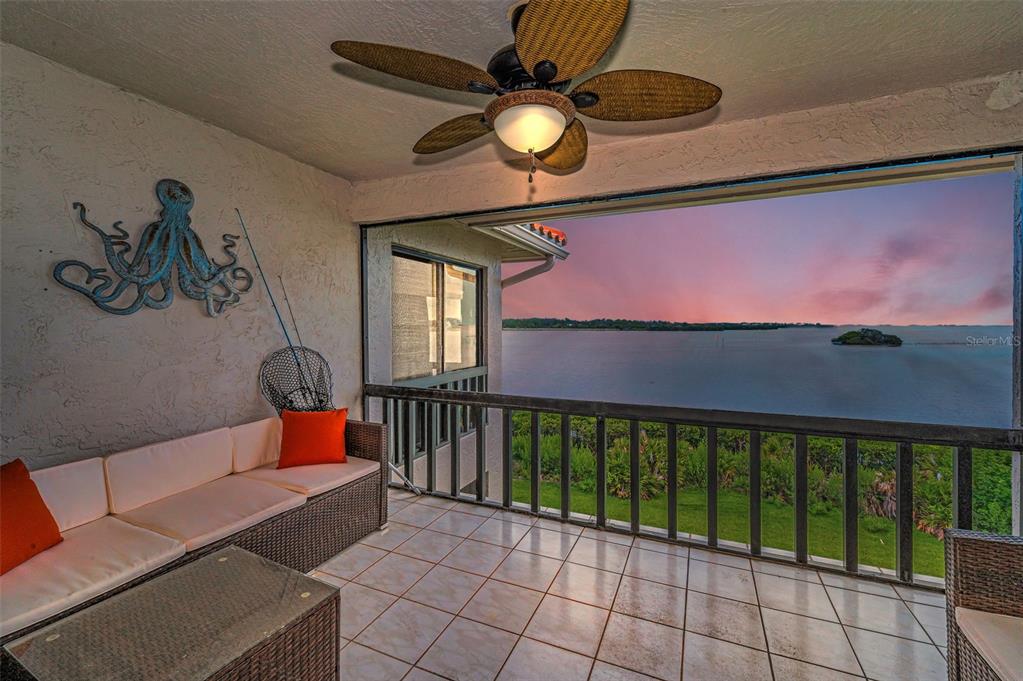 A covered balcony features wicker furniture, an octopus wall decoration, and a view of water — 1813 MARINER DRIVE UNIT 146, TARPON SPRINGS, FL