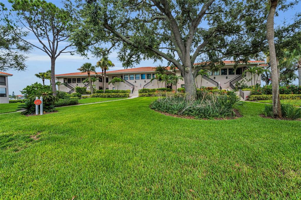 A two-story apartment building with a red tile roof sits behind a large grassy lawn — 1813 MARINER DRIVE UNIT 146, TARPON SPRINGS, FL