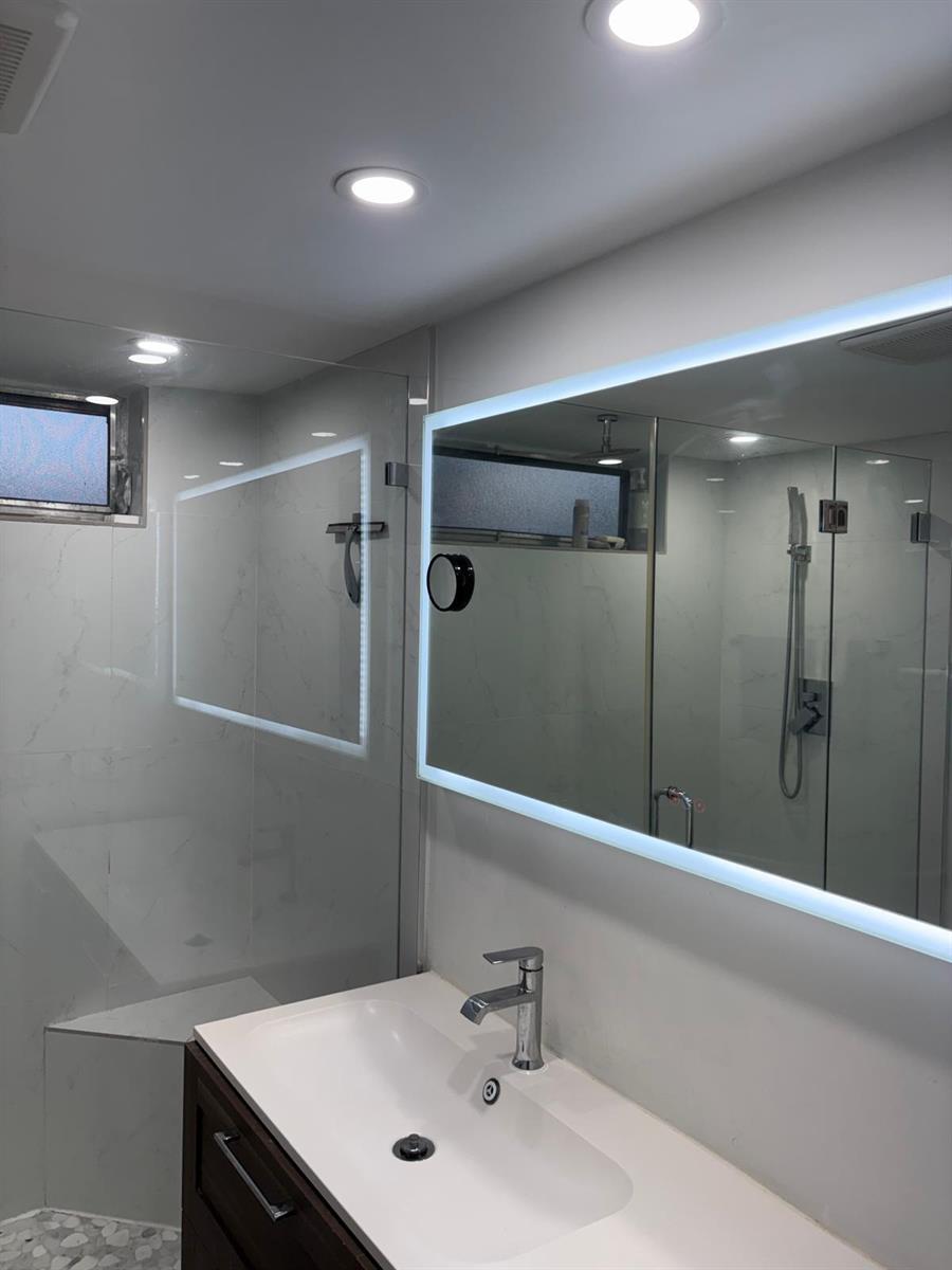 A modern bathroom features a white vanity, a backlit mirror, and a glass-enclosed shower — 20 SE 13th Street # B7, Boca Raton FL 33432, BOCA RATON, FL