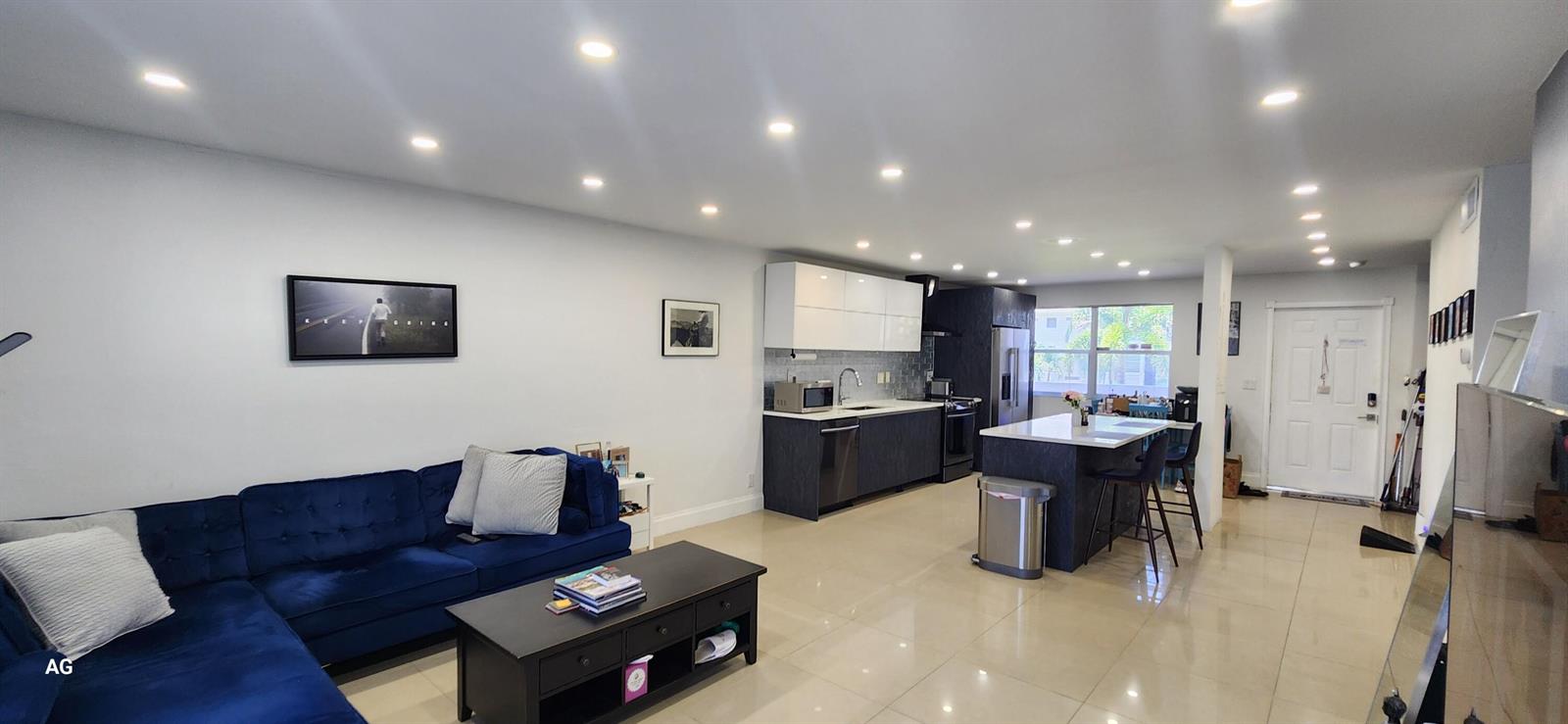An open-concept living room and kitchen with a blue sectional sofa and a kitchen island — 20 SE 13th Street # B7, Boca Raton FL 33432, BOCA RATON, FL