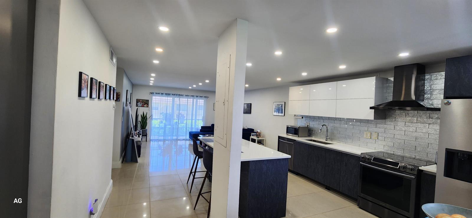 An open-concept kitchen features dark lower cabinets, white upper cabinets, and a central island — 20 SE 13th Street # B7, Boca Raton FL 33432, BOCA RATON, FL