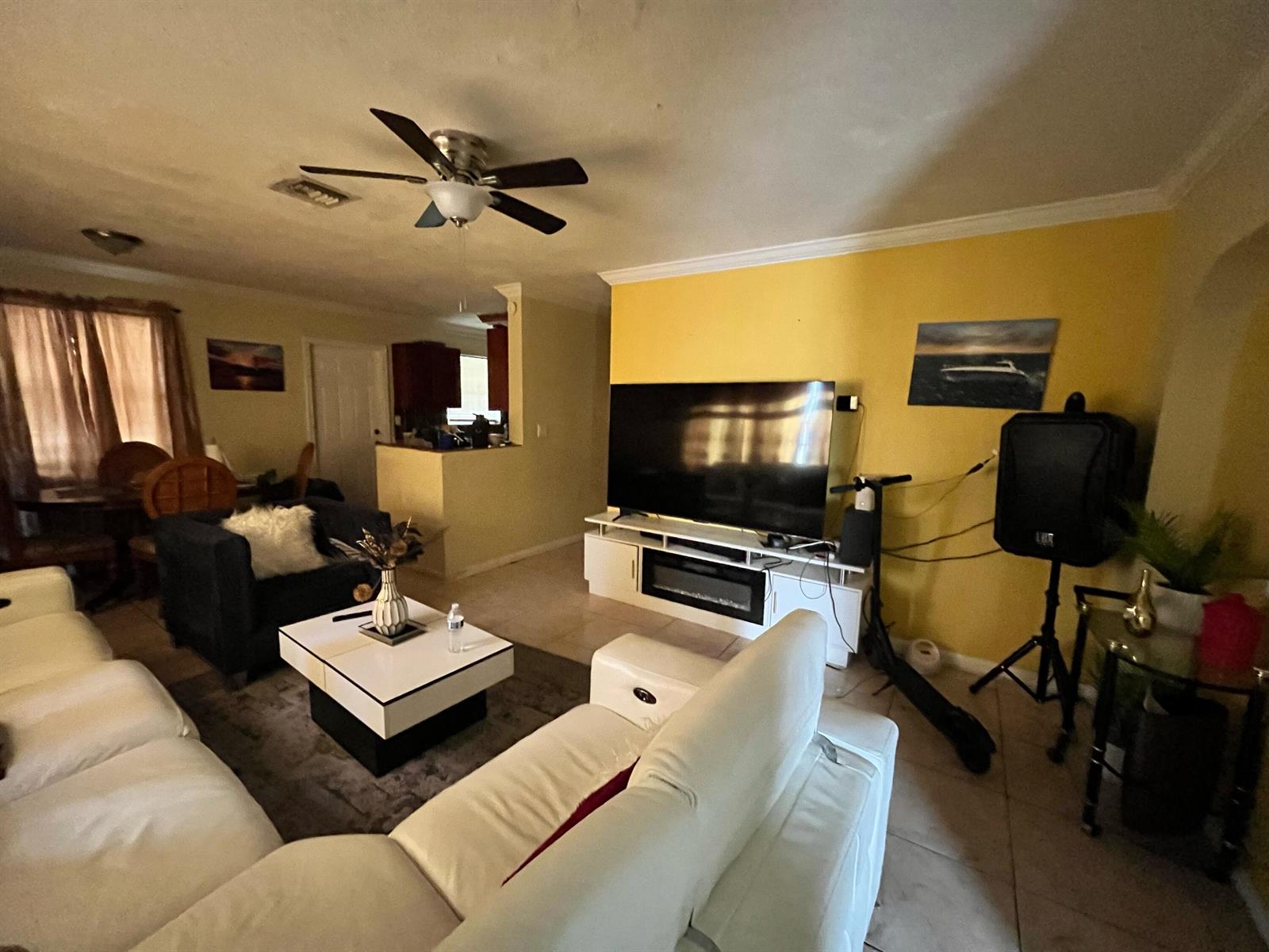 A living room features a white sectional sofa, a television on a stand, and yellow walls — 4730 NE 2nd Avenue NE, Deerfield Beach FL 33064, DEERFIELD BEACH, FL