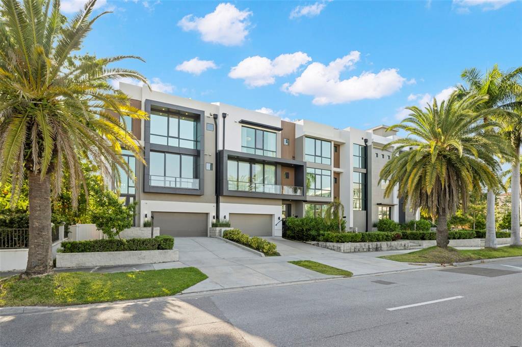 A modern multi-story townhouse complex features large windows, balconies, and attached garages with palm trees — 98 W DAVIS BOULEVARD, TAMPA, FL
