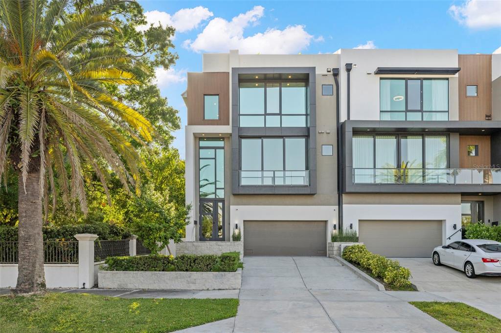 A modern three-story townhouse with a two-car garage, large windows, and a palm tree — 98 W DAVIS BOULEVARD, TAMPA, FL