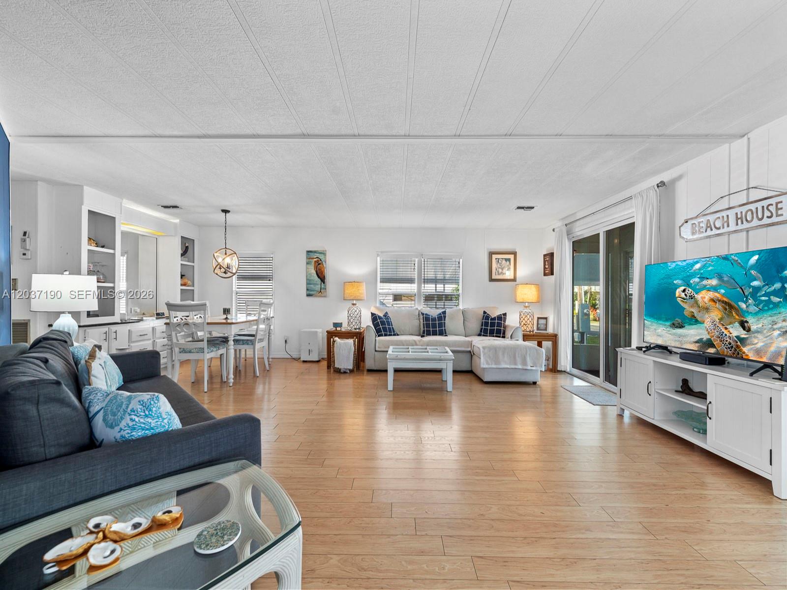 A bright living room features light wood flooring, a sectional sofa, and a television — 806 S Jade Dr # 806, Key Largo FL 33037, KEY LARGO, FL