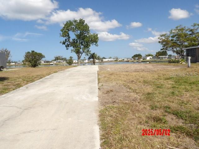 A concrete driveway leads toward a vacant waterfront lot under a blue sky — 6245 ORIOLE BOULEVARD, ENGLEWOOD, FL