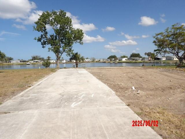 A concrete driveway leads toward a waterfront view with trees and distant houses — 6245 ORIOLE BOULEVARD, ENGLEWOOD, FL