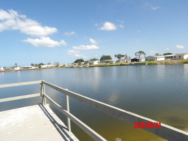 A wooden dock overlooks a calm lake with houses along the distant shoreline — 6245 ORIOLE BOULEVARD, ENGLEWOOD, FL