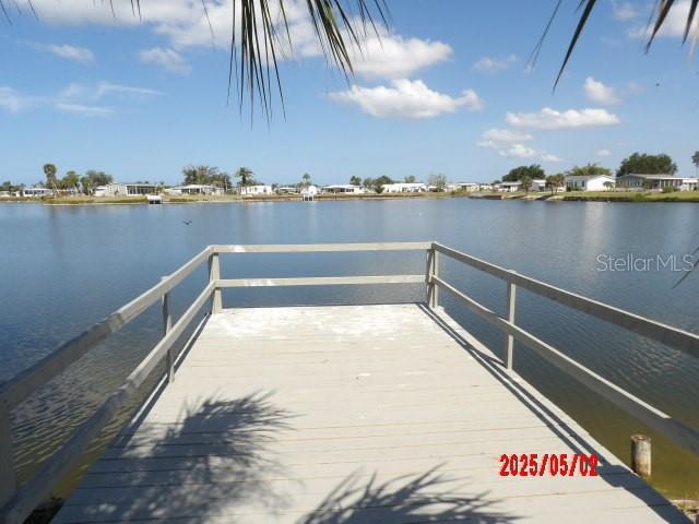 A wooden dock extends over a calm lake toward a shoreline with several houses — 6245 ORIOLE BOULEVARD, ENGLEWOOD, FL