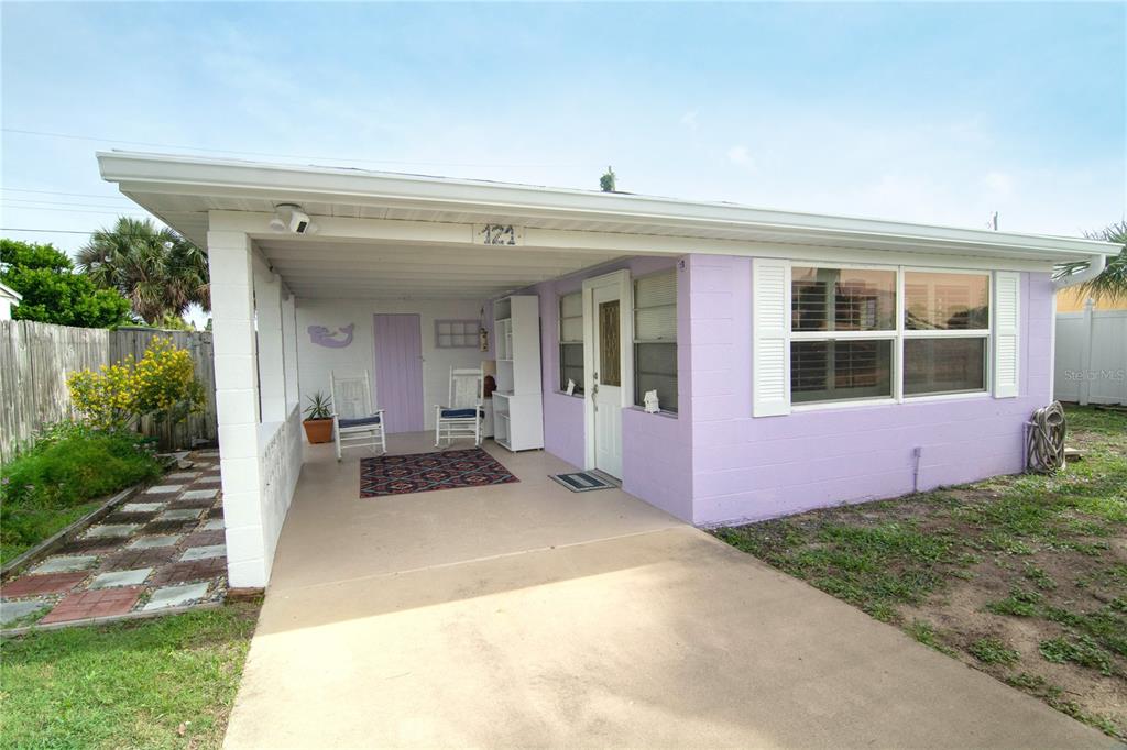 A light purple house features a covered carport with a concrete floor and white trim — 121 LAURIE DRIVE, ORMOND BEACH, FL
