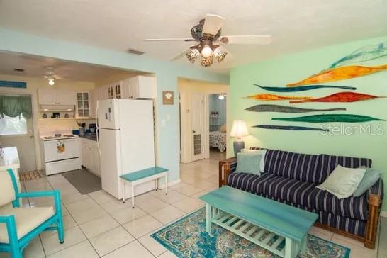 A living room with a striped sofa, teal coffee table, and an open kitchen area — 121 LAURIE DRIVE, ORMOND BEACH, FL