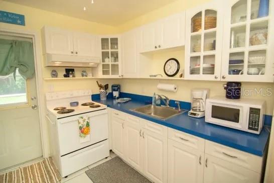 A kitchen features white cabinets, a blue countertop, a white stove, and a microwave — 121 LAURIE DRIVE, ORMOND BEACH, FL