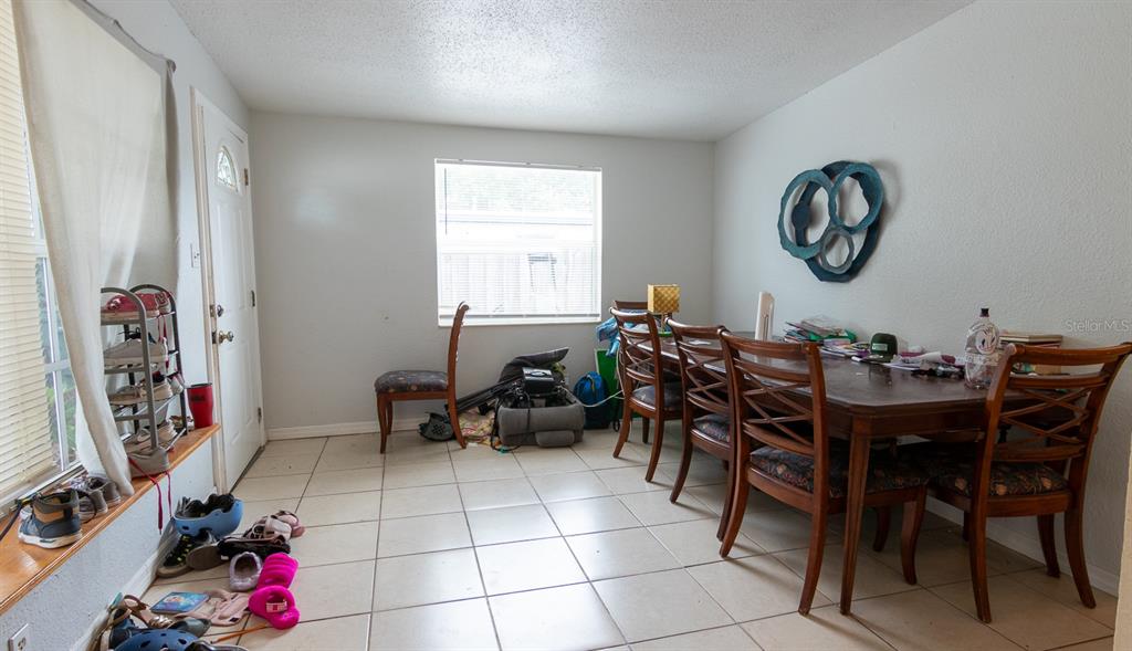 A dining room with tile flooring, a wooden table with chairs, and a window — 3731 PAPAI DRIVE, SARASOTA, FL