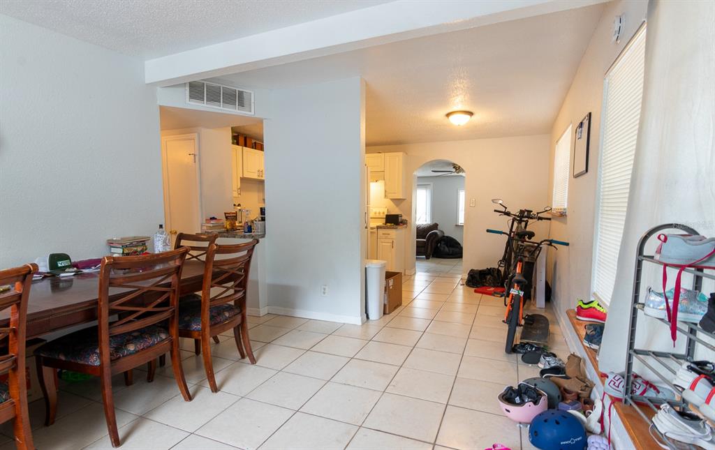 A dining area with tile floors leads to a kitchen and a living room beyond — 3731 PAPAI DRIVE, SARASOTA, FL
