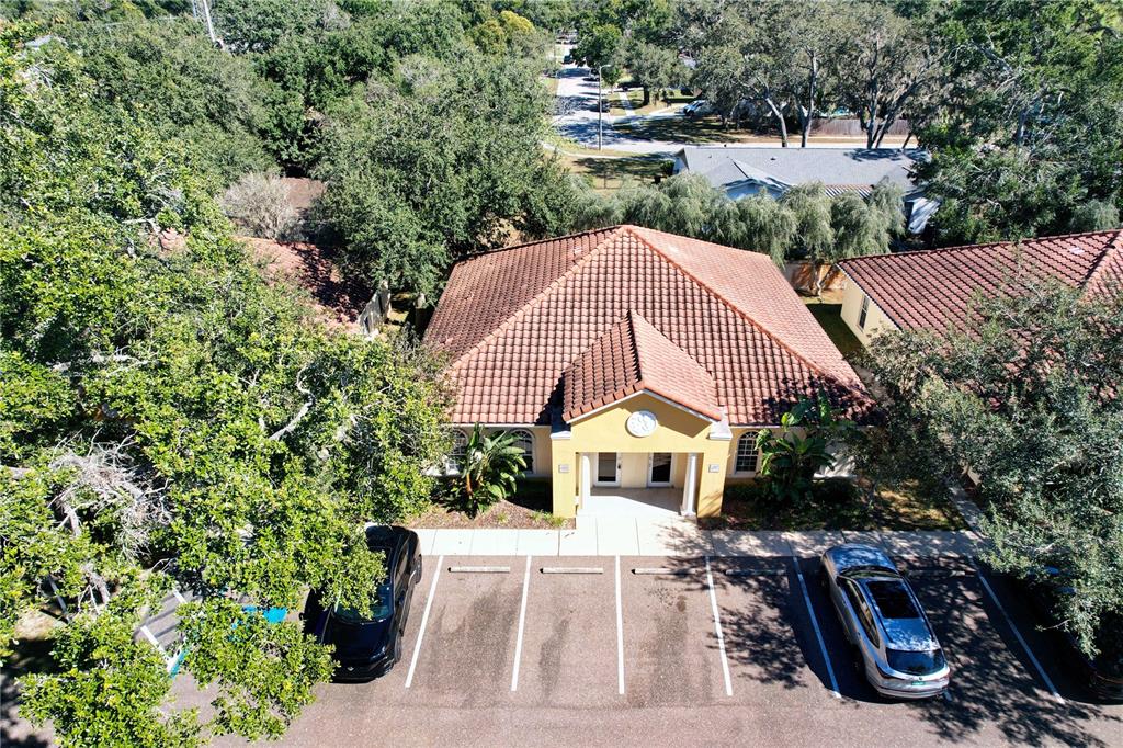 An aerial view shows a yellow building with a tiled roof and a parking lot — 6957 E FOWLER AVENUE, TAMPA, FL