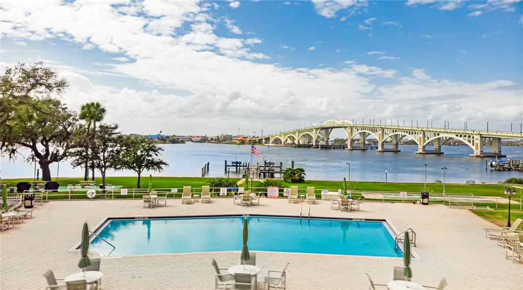 An outdoor swimming pool overlooks a grassy lawn, a boat dock, and a large bridge — 1224 S PENINSULA DRIVE UNIT 415, DAYTONA BEACH, FL