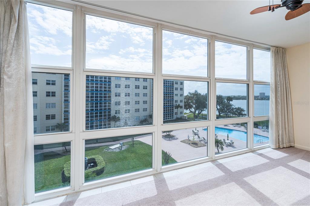 A room with floor-to-ceiling windows overlooking a swimming pool, courtyard, and a body of water — 1224 S PENINSULA DRIVE UNIT 415, DAYTONA BEACH, FL