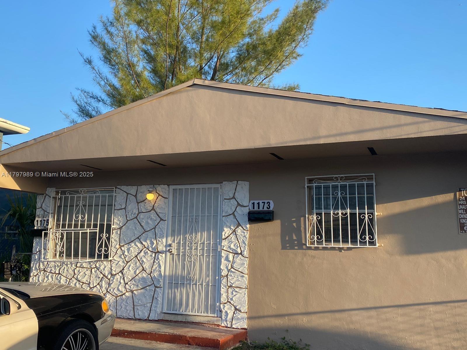 A single-story house exterior features a stone-accented entryway, security bars on windows, and a driveway — 1173 NW 65th St, Miami FL 33150, MIAMI, FL