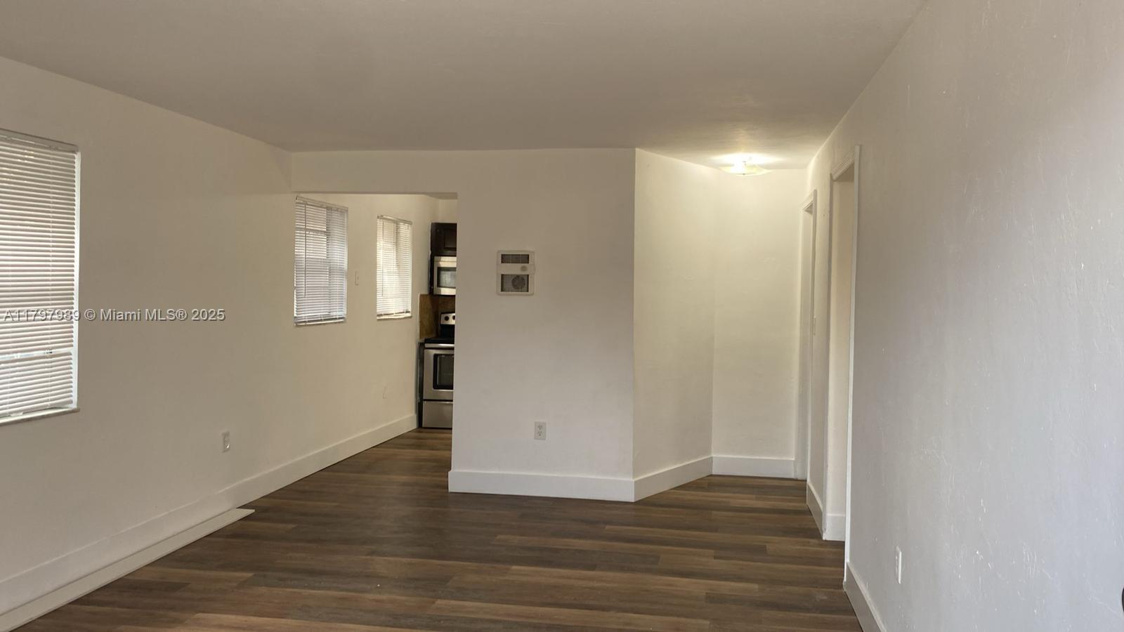 An interior view shows a living area with wood-look flooring leading to a kitchen — 1173 NW 65th St, Miami FL 33150, MIAMI, FL
