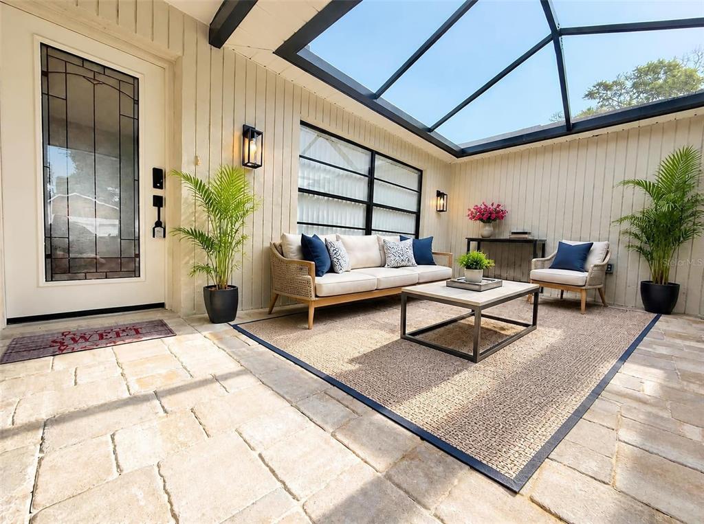 A sunroom features a glass roof, stone tile flooring, a sofa, and a coffee table — 2801 NARCISSUS DRIVE, HOLIDAY, FL