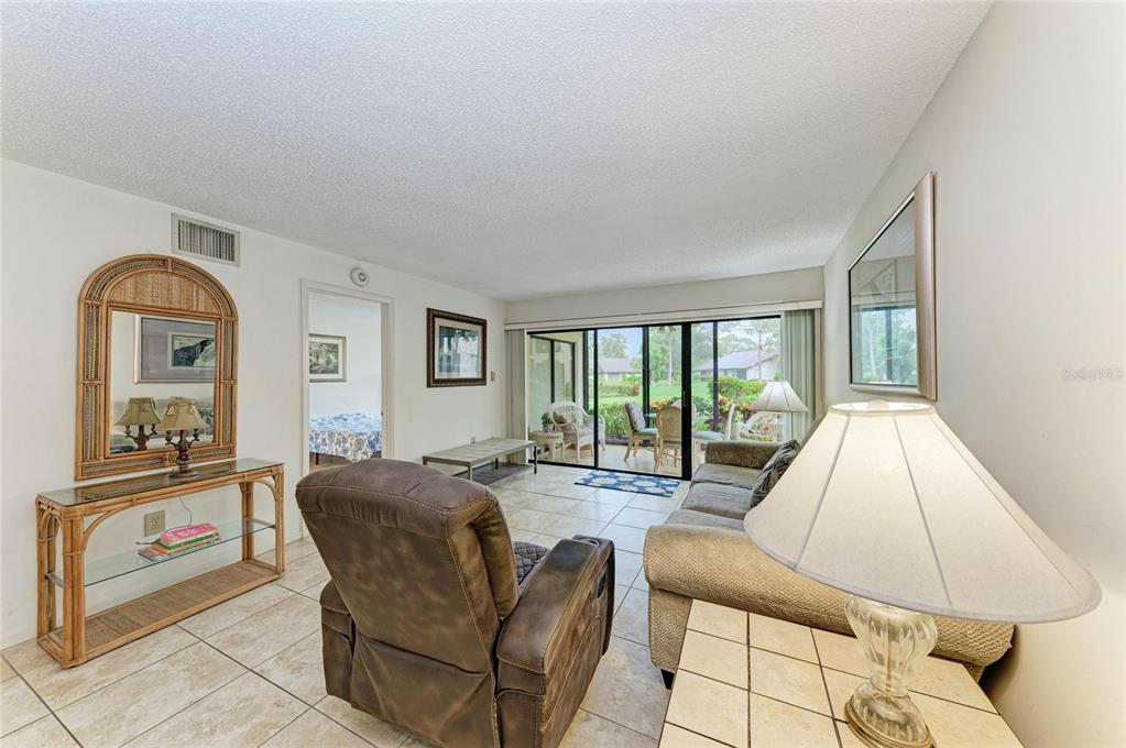A living room with tile floors, a recliner, a sofa, and a sliding glass door — 5200 LAKE VILLAGE DRIVE UNIT 79, SARASOTA, FL
