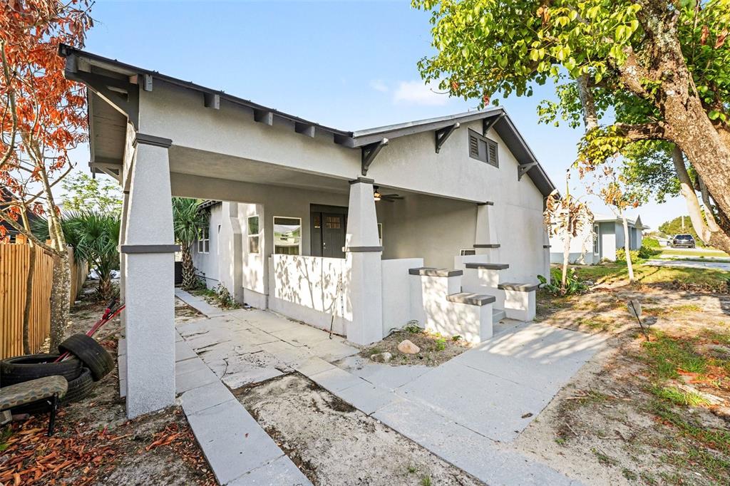 A gray house exterior features a covered carport, a front porch, and concrete steps — 129 W PARK AVENUE, LAKE WALES, FL