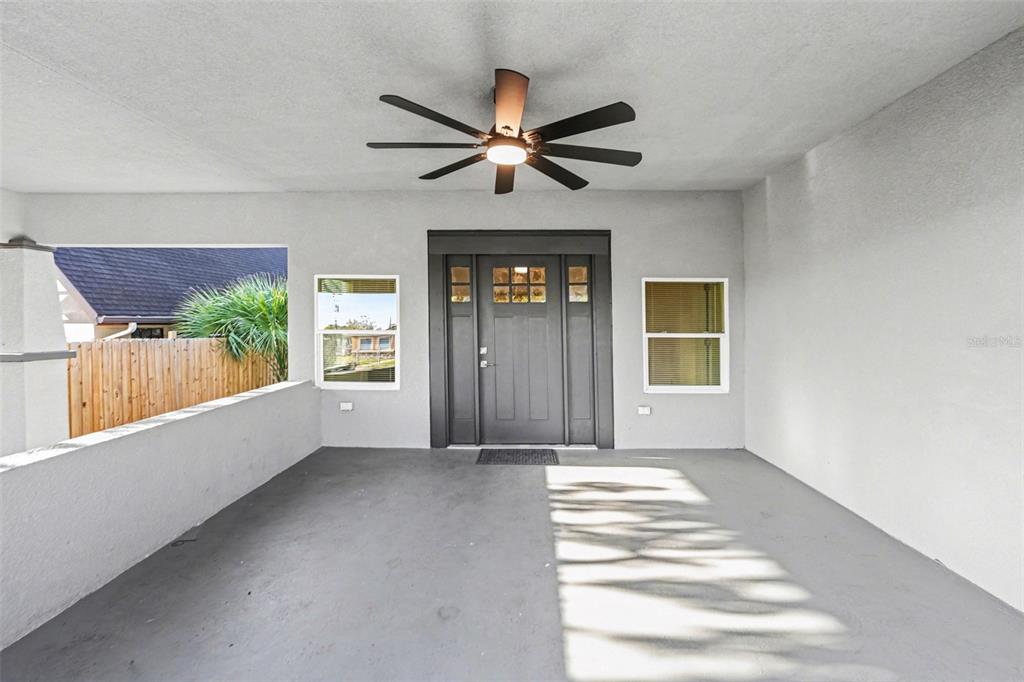 A covered porch features a gray door, two windows, and a ceiling fan — 129 W PARK AVENUE, LAKE WALES, FL