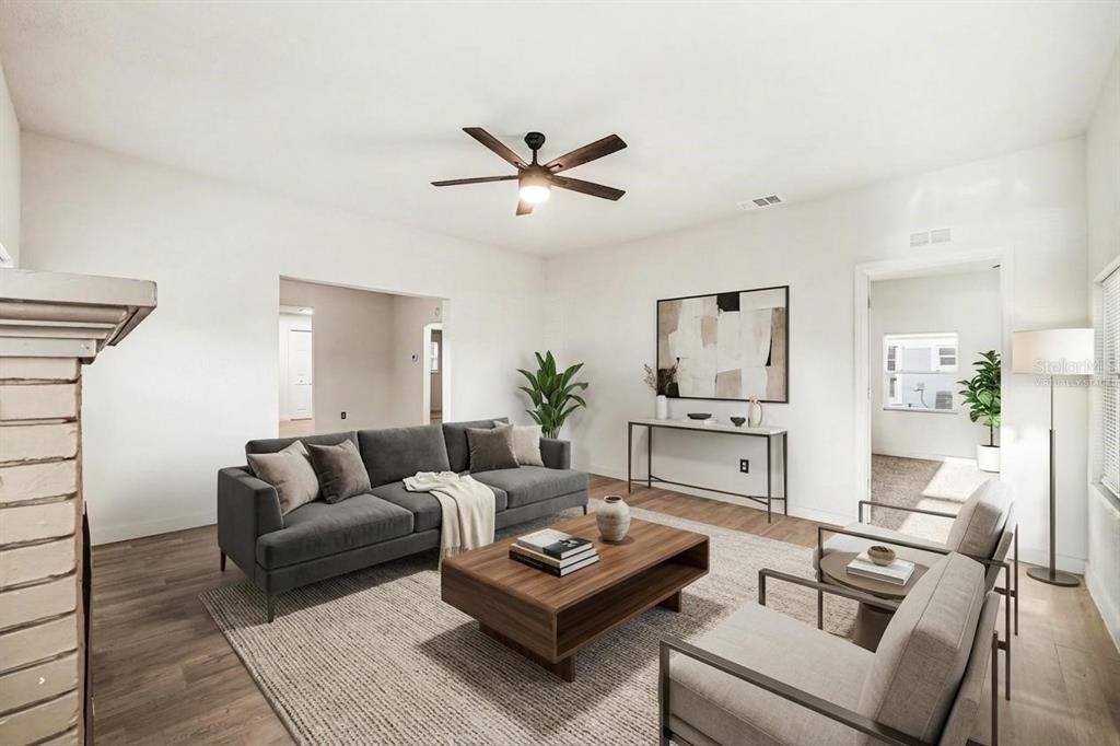 A living room with a gray sofa, wood coffee table, and light wood-look flooring — 129 W PARK AVENUE, LAKE WALES, FL