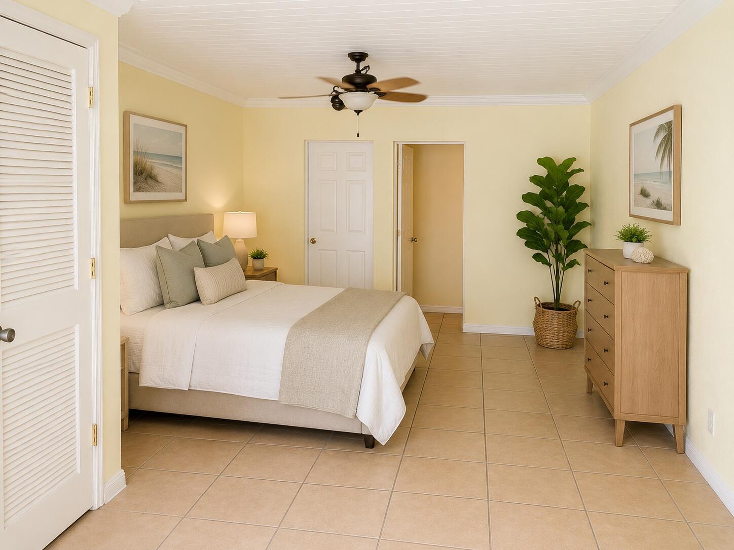 A bedroom with light yellow walls, tile flooring, a queen bed, and a wooden dresser — 105 Ave D Unit B, Fort Pierce FL 34950, FORT PIERCE, FL