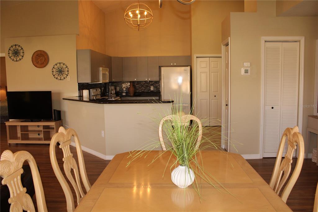A dining area with a light wood table faces an open kitchen with gray cabinets — 3115 LIVE OAK LANE UNIT 30, PALMETTO, FL