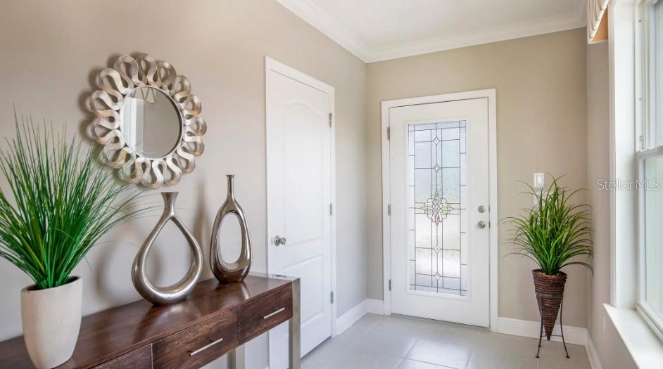 An entryway features a console table, a decorative mirror, two vases, and a glass-paneled door — 3828 BLUETHREAD WAY, POINCIANA, FL