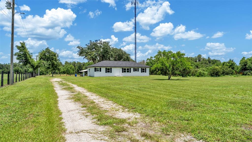 A white house with a dark roof sits on a large, grassy lot — 11637 US HIGHWAY 98 N, LAKELAND, FL