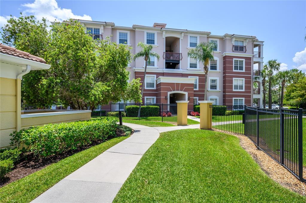 A multi-story apartment building with a sidewalk leading to the entrance and landscaped grounds — 5012 SHOREWAY LOOP UNIT 20507, ORLANDO, FL