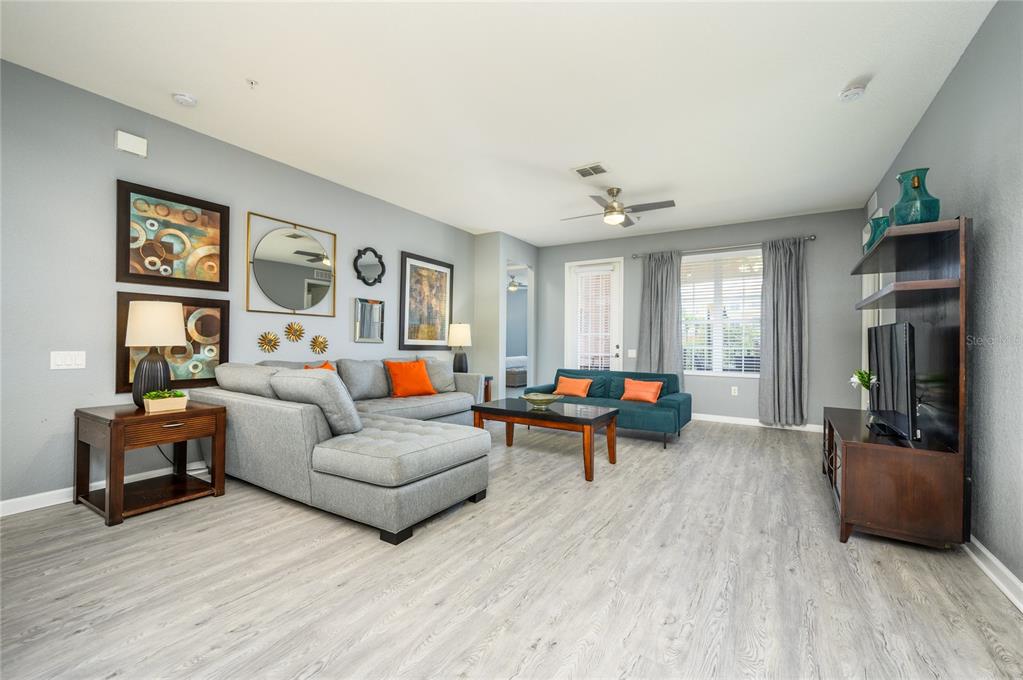 A living room features a grey sectional sofa, a teal loveseat, and wood-toned furniture — 5012 SHOREWAY LOOP UNIT 20507, ORLANDO, FL
