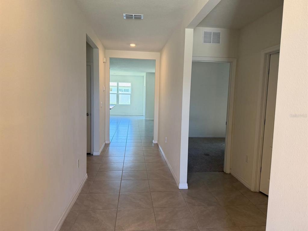 A tiled hallway leads toward a bright living area with a window and carpeted room — 4604 BERNARD BOULEVARD, HAINES CITY, FL