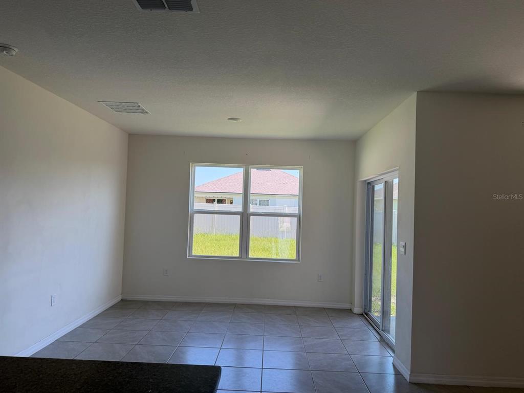 An empty room with tile flooring, a window, and sliding glass doors leading outside — 4604 BERNARD BOULEVARD, HAINES CITY, FL