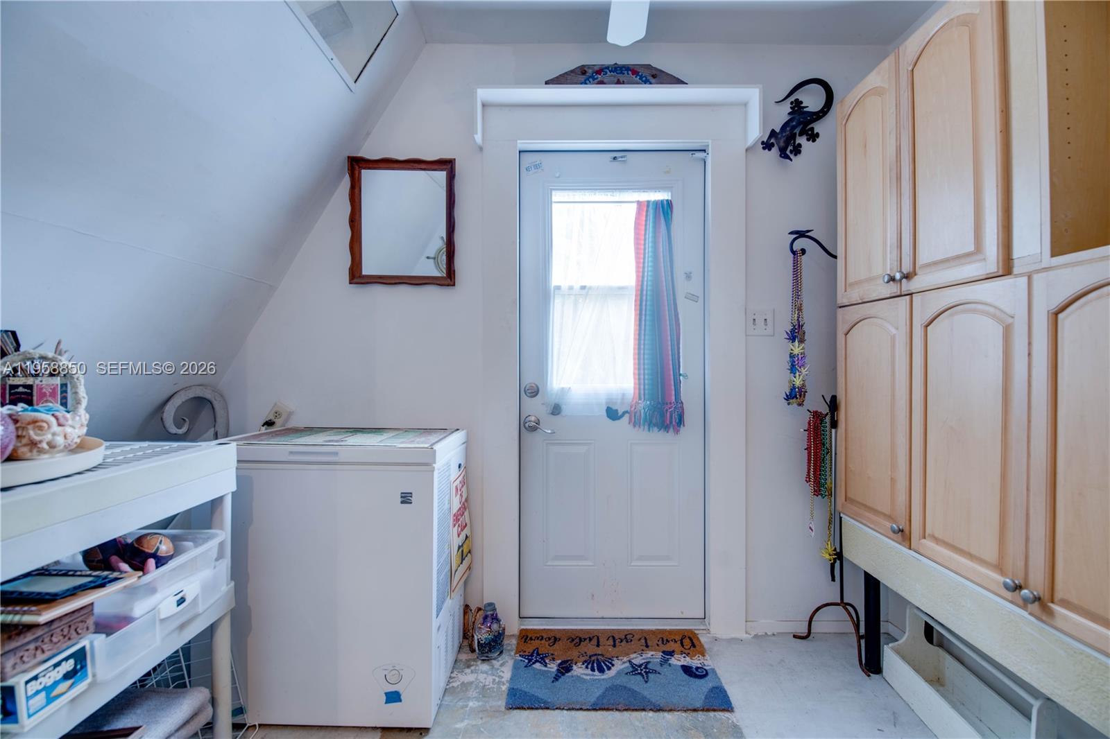 A laundry room features a chest freezer, a white door, and light wood cabinets — 31033 Hibiscus Dr, Big Pine FL 33043, BIG PINE, FL