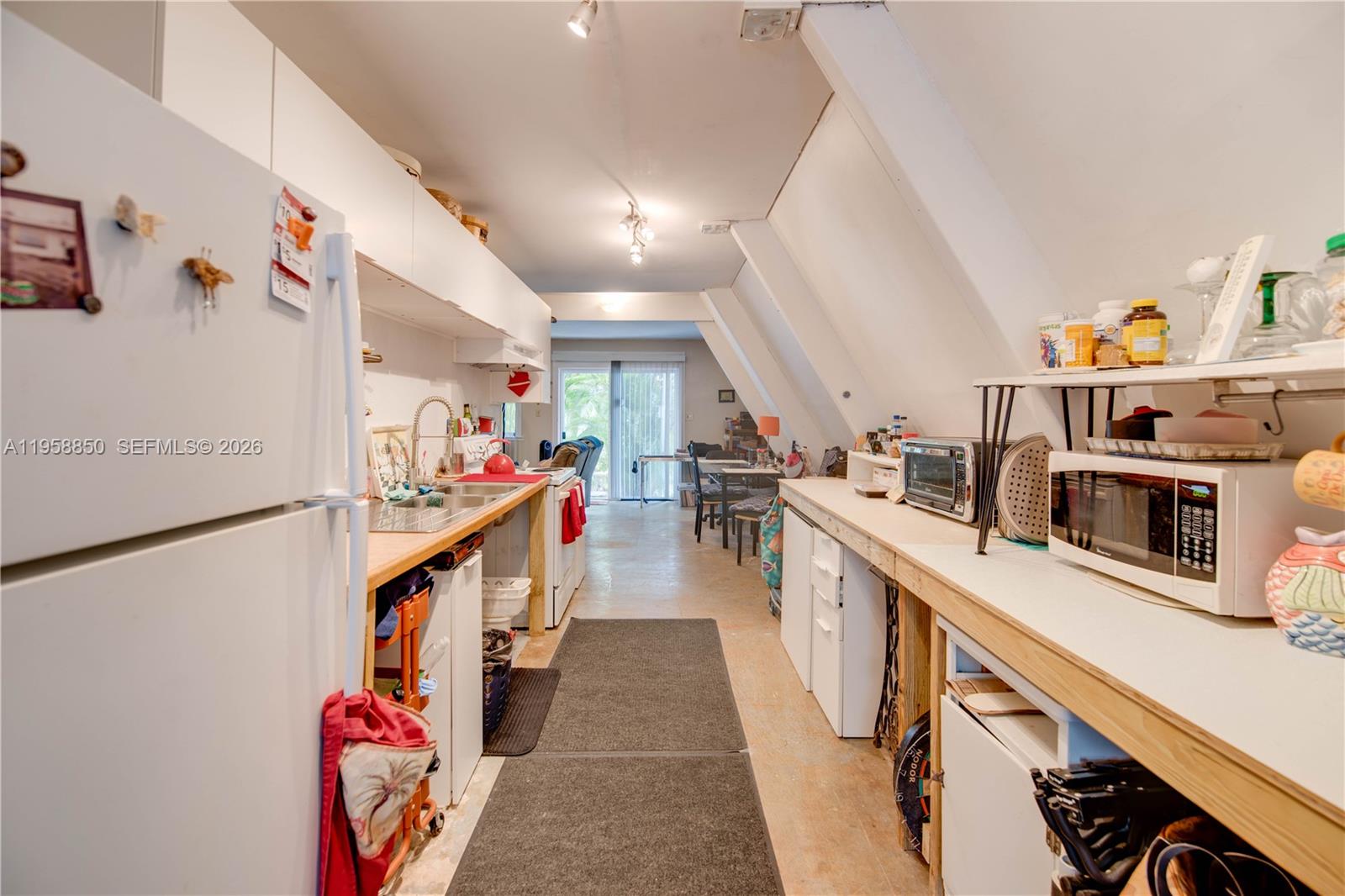 A narrow kitchen features white cabinets, wooden countertops, and a sloped ceiling — 31033 Hibiscus Dr, Big Pine FL 33043, BIG PINE, FL