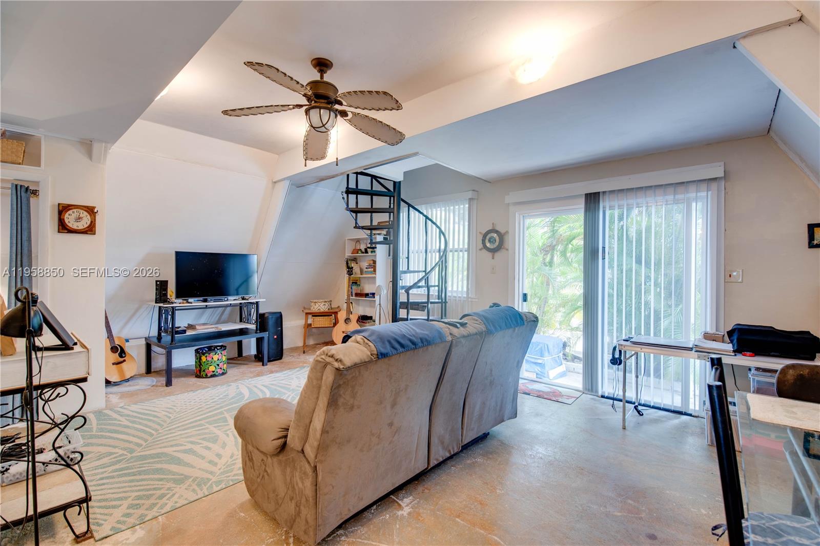 A living room features a spiral staircase, a sofa, a television, and sliding glass doors — 31033 Hibiscus Dr, Big Pine FL 33043, BIG PINE, FL