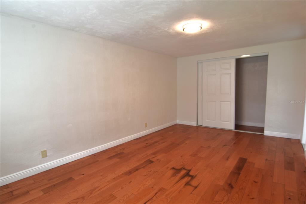 A bedroom with light-colored walls, hardwood flooring, and a sliding closet door — 941 HARTFORD AVENUE, DAYTONA BEACH, FL