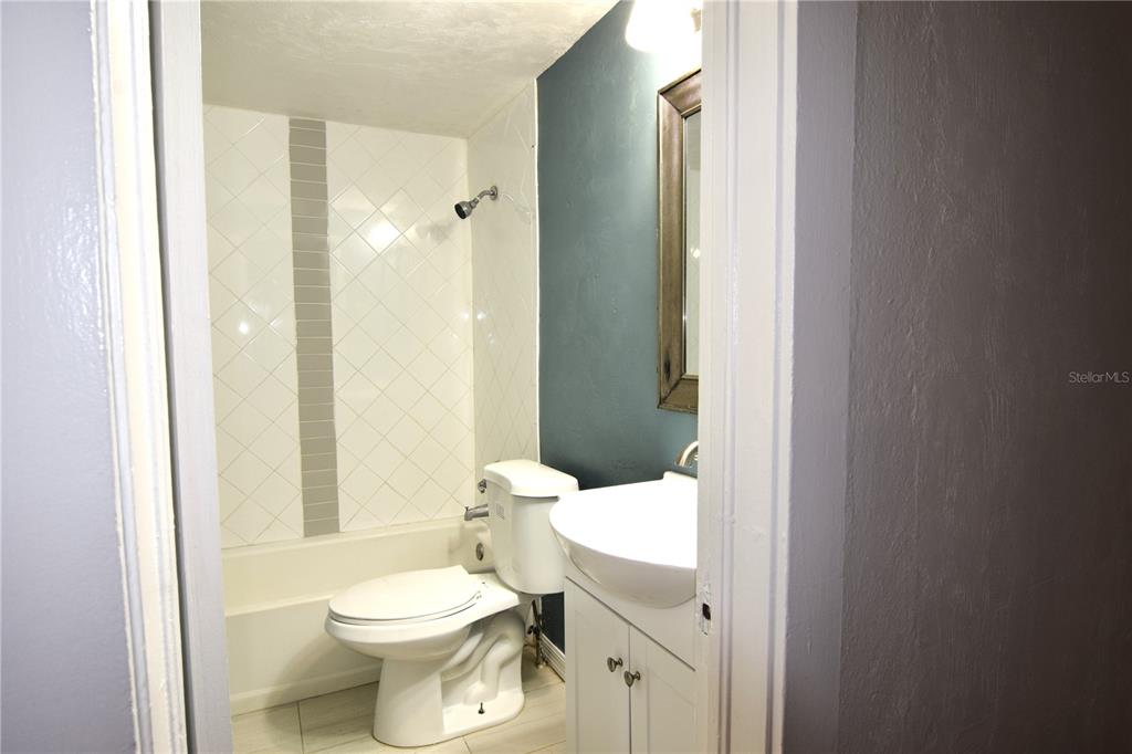 A bathroom features a white toilet, a pedestal sink, and a tiled shower-tub combination — 941 HARTFORD AVENUE, DAYTONA BEACH, FL