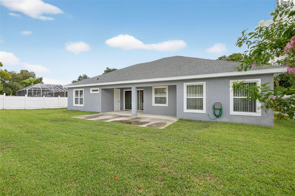 The exterior of a gray house features a concrete patio and a white vinyl fence — 46 FURNESS PLACE, PALM COAST, FL