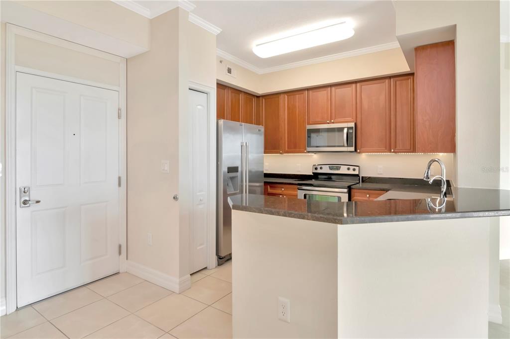 A kitchen features wood cabinets, stainless steel appliances, and a dark granite breakfast bar — 4516 SEAGULL DRIVE UNIT 916, NEW PORT RICHEY, FL