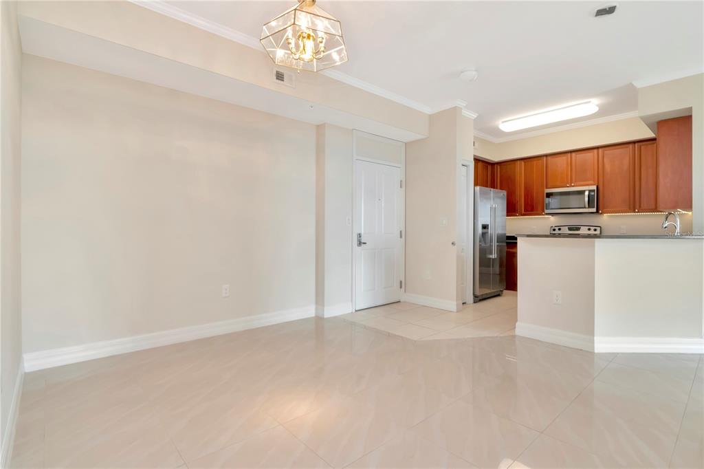 An open-concept dining area features tile flooring, a geometric light fixture, and an adjacent kitchen — 4516 SEAGULL DRIVE UNIT 916, NEW PORT RICHEY, FL
